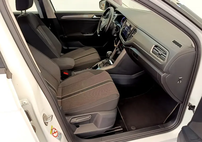 Intérieur avant droit d'un Volkswagen T-Roc blanc 2021, sièges tissu gris et tableau de bord moderne avec écran tactile.