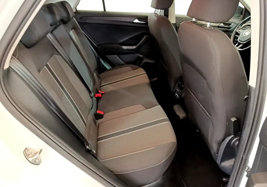 Vue intérieure côté gauche sur la banquette arrière noire du Volkswagen T-Roc blanc, avec sièges tissu et appuie-têtes.