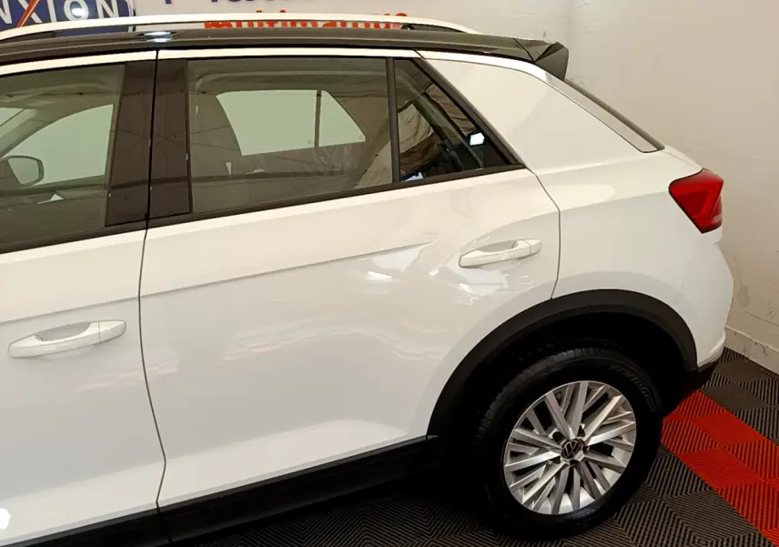 Vue latérale côté droit du Volkswagen T-Roc blanc, mettant en valeur la porte arrière et la roue arrière avec jante alliage.