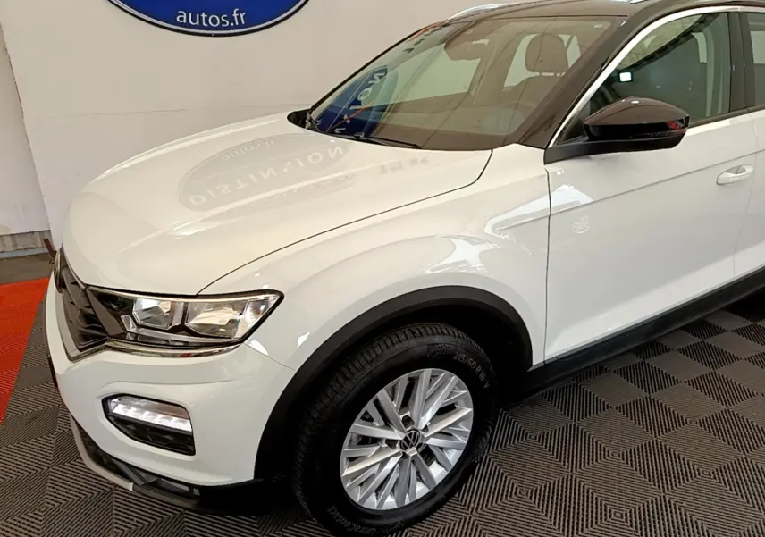 Vue 3/4 avant droit d'un Volkswagen T-Roc blanc avec jantes alliage et rétroviseurs noirs brillants.
