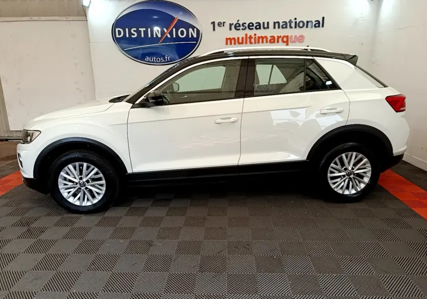 Profil côté gauche d'un Volkswagen T-Roc blanc 2021 avec jantes alliage et toit noir en showroom.