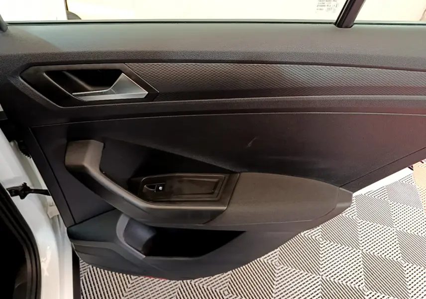 Vue côté gauche de la porte intérieure noire du Volkswagen T-Roc blanc avec poignée et commande de vitre électrique.