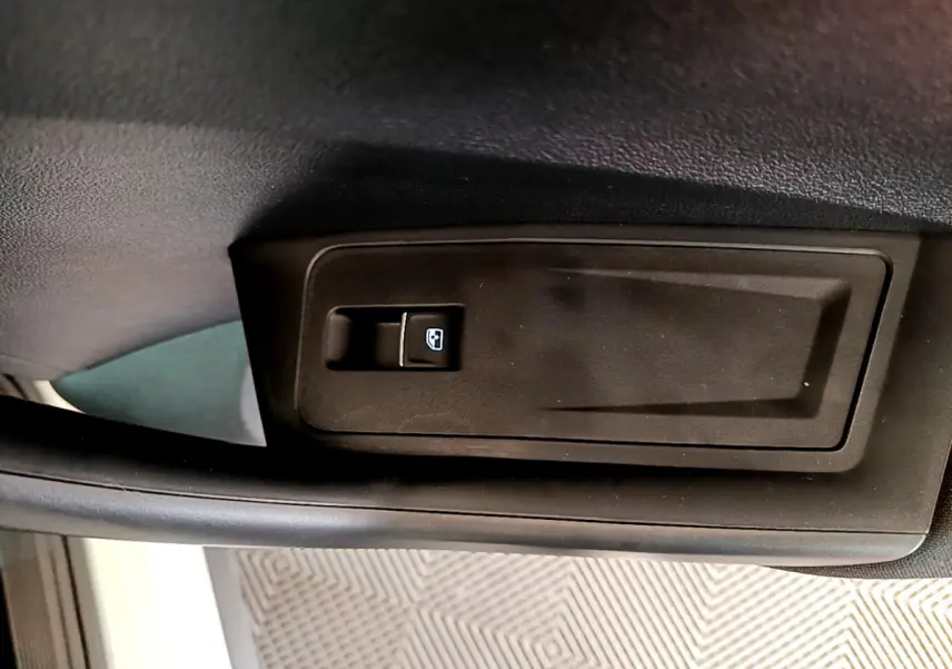 Gros plan sur la commande de lève-vitre côté conducteur du Volkswagen T-Roc blanc, intérieur noir.