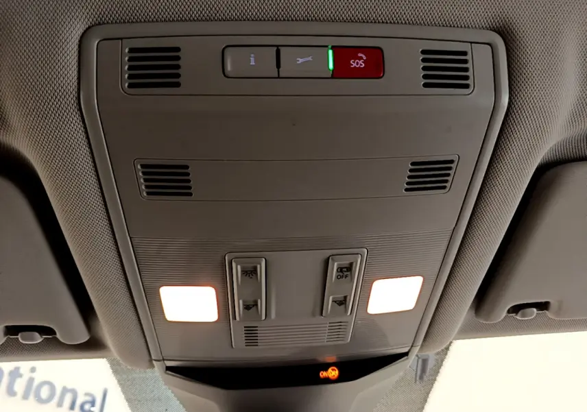 Vue intérieure du plafonnier avant du Volkswagen T-Roc blanc 2021 avec éclairage et bouton SOS activé.