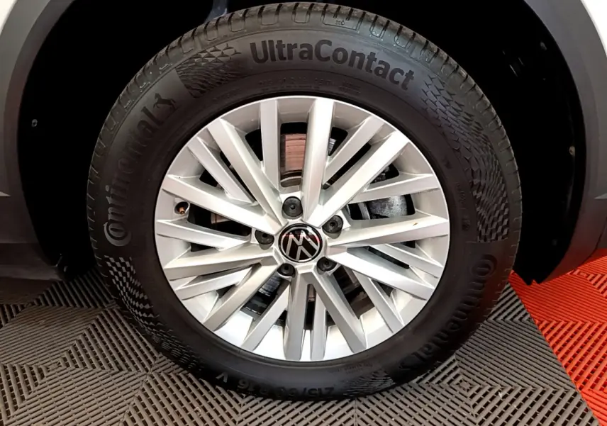 Gros plan sur la jante argentée en alliage du Volkswagen T-Roc blanc, mettant en valeur le logo VW central.