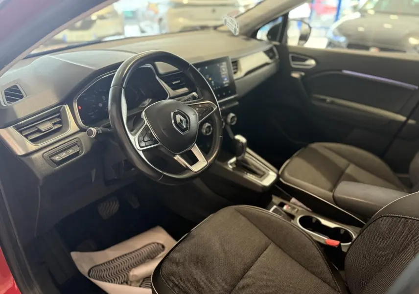 Vue intérieure côté conducteur du Renault Captur 2020, avec volant cuir, console centrale et sièges tissu noirs.