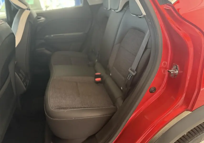 Vue intérieure côté arrière droit du Renault Captur 2020 rouge foncé, montrant les sièges arrière en tissu gris et noir.