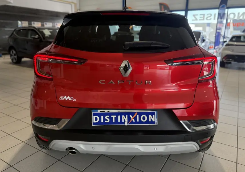 Vue arrière d'un Renault Captur rouge foncé dans un showroom, avec logo et plaque Distinxion visibles.