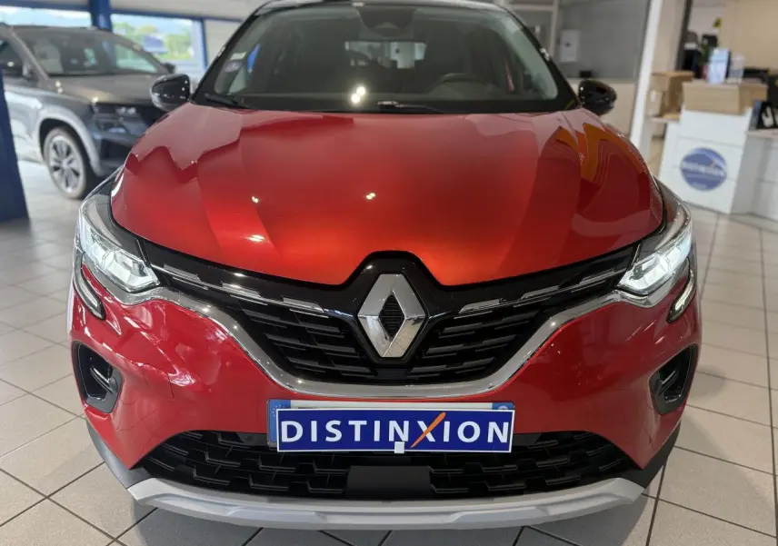Vue frontale d'un Renault Captur rouge foncé avec calandre noire et logo Renault bien visible en showroom.