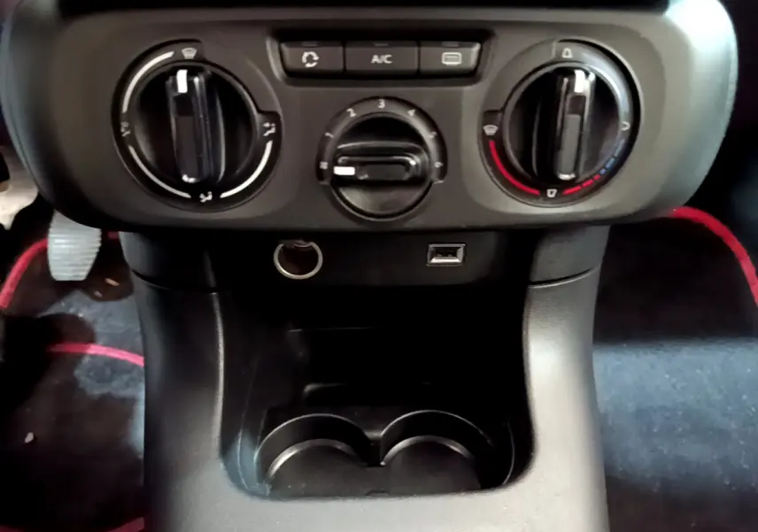 Vue rapprochée de la console centrale noire de la Citroën C3 avec commandes de climatisation et prises USB et 12V.