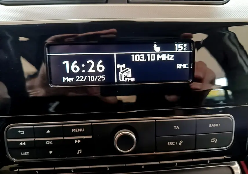 Affichage central de la radio et horloge sur tableau de bord noir brillant d'une Citroën C3 blanche de 2018.