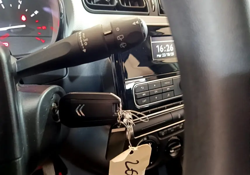 Vue rapprochée de l’intérieur d’une Citroën C3 blanche 2018, montrant la clé dans le contact et le tableau de bord noir.