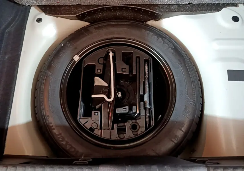 Vue plongeante sur la roue de secours noire dans le coffre blanc d'une Citroën C3 PureTech 68 BVM Live 2018.