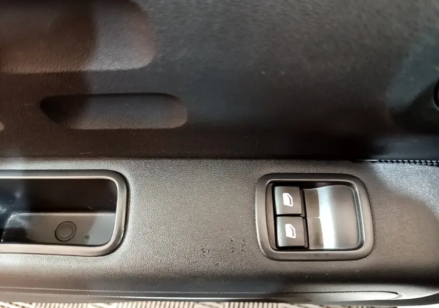 Gros plan sur les commandes des vitres électriques côté conducteur d'une Citroën C3 blanche, version PureTech 68 BVM Live.