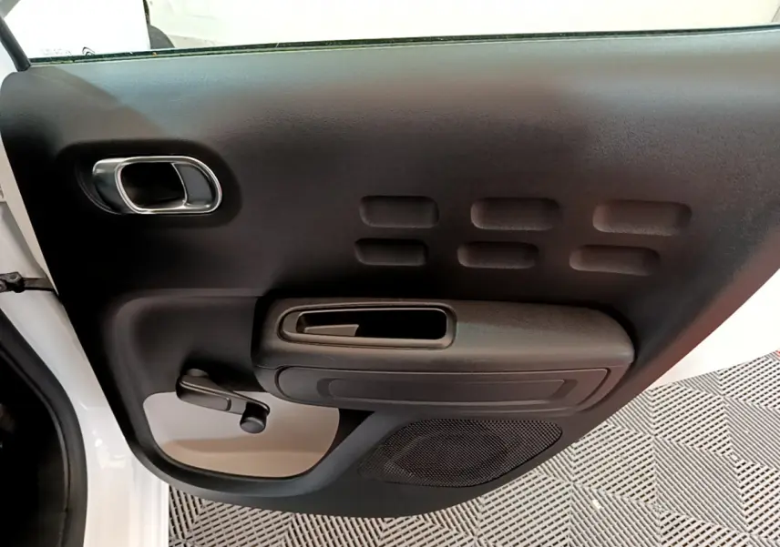 Vue rapprochée de la porte arrière gauche blanche d’une Citroën C3 2018, avec poignée et manivelle de vitre noire.