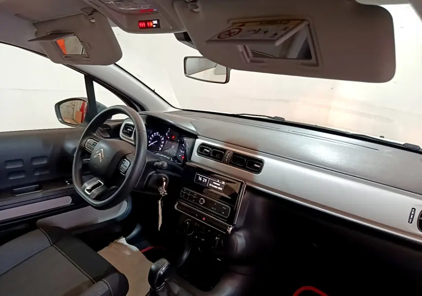 Vue intérieure côté conducteur du tableau de bord noir et gris de la Citroën C3 blanche avec volant multifonction et levier de vitesse manuel.