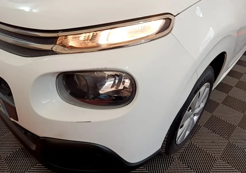 Gros plan sur l'avant droit blanc d'une Citroën C3 2018 avec phare allumé et jante visible.