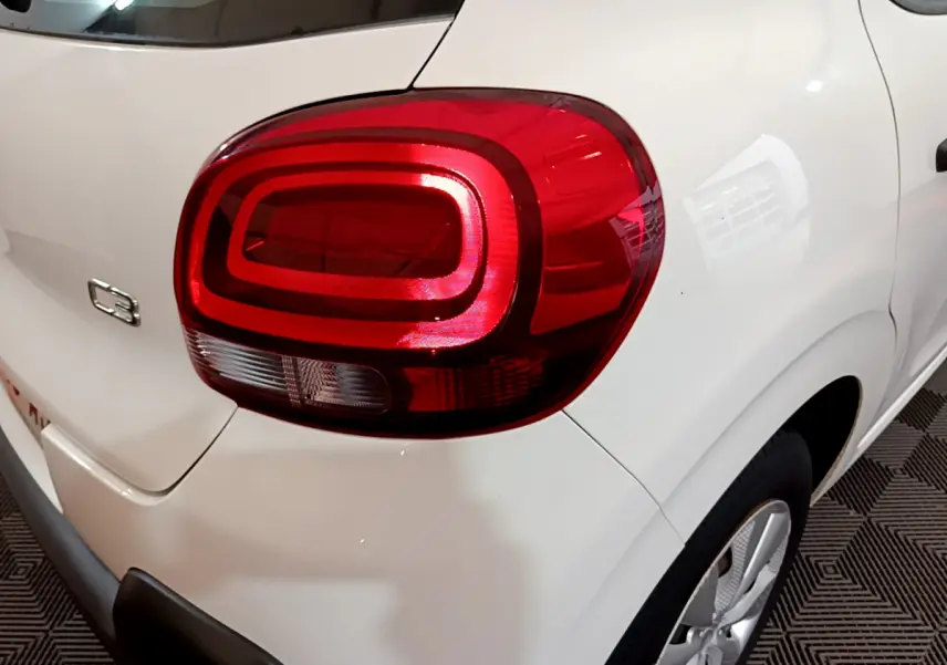 Gros plan sur le feu arrière droit rouge d'une Citroën C3 blanche, avec logo C3 visible sur la carrosserie.