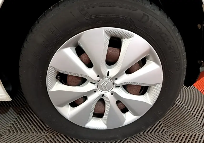 Gros plan sur la roue avant droite d'une Citroën C3 blanche de 2018 avec enjoliveur argenté au design moderne.