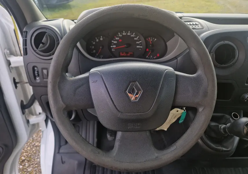 Vue intérieure centrée sur le volant noir du Renault Master Planche Cabine blanc, avec tableau de bord et compteurs visibles.