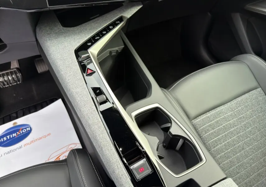 Vue intérieure rapprochée du console central gris clair et noir avec sièges tissu et cuir gris du Peugeot 3008 blanc 2025.