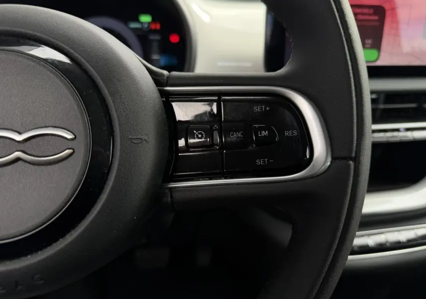 Gros plan sur le volant noir Soft-Touch de la Fiat 500 électrique 2024 avec commandes de régulateur de vitesse.