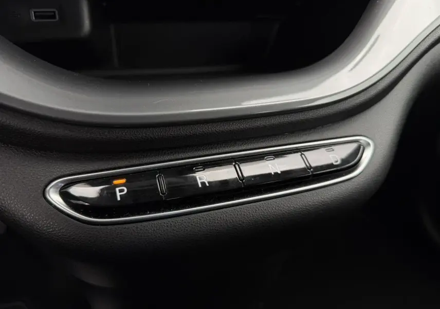 Gros plan sur la commande de boîte automatique noire avec indication orange sur la position "P" dans une Fiat 500 électrique blanche.