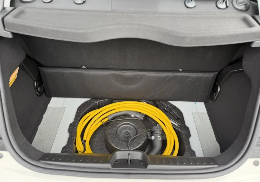 Coffre ouvert d'une Fiat 500 électrique blanc Artic, montrant le câble de recharge jaune rangé sous la trappe.