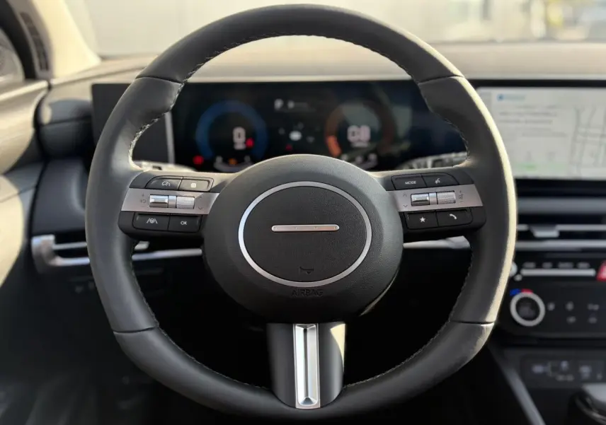 Volant en cuir noir de la Hyundai Tucson 2025 avec commandes intégrées et tableau de bord numérique en arrière-plan.