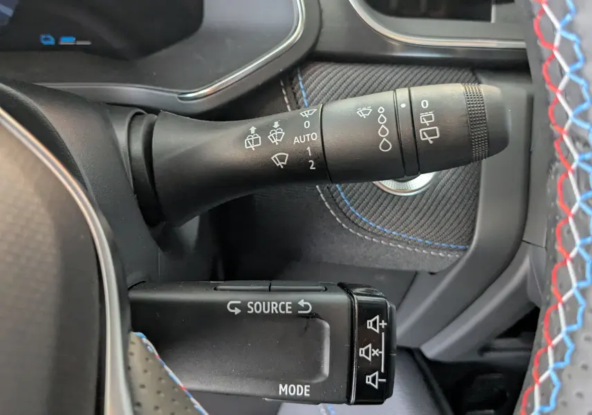 Gros plan sur les commandes de volant du Renault Symbioz bleu iron, avec détails des commandes d'essuie-glace et audio.
