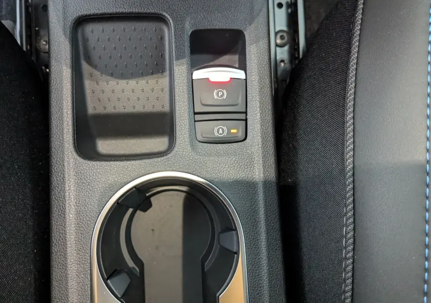 Gros plan sur la console centrale du Renault Symbioz bleu iron, avec boutons de frein à main et rangement.