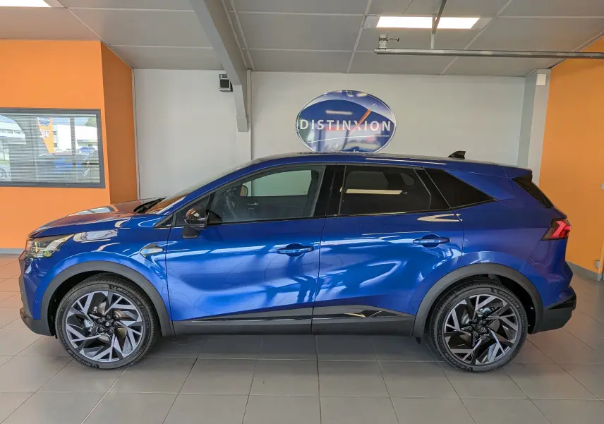Profil droit du Renault SYMBIOZ E-TECH Full Hybrid 145ch Esprit Alpine en bleu Iron avec jantes biton et toit noir en showroom.