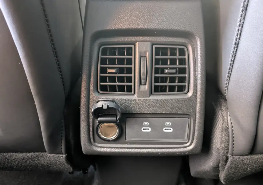 Détail de la console arrière avec prises USB et prise 12V entre les sièges noirs du Renault Symbioz E-Tech Hybrid 2025.