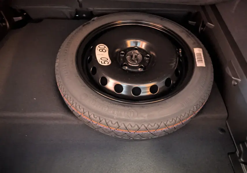 Roue de secours noire en gros plan dans le coffre d'une Renault Symbioz E-Tech Full Hybrid 2025.