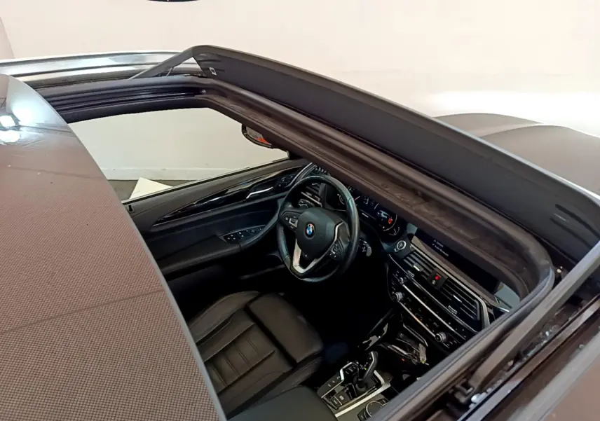 Vue plongeante sur l'intérieur noir d'une BMW X3 2019 avec toit ouvrant et tableau de bord moderne.