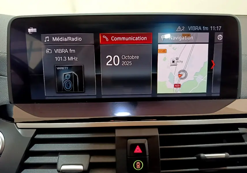 Écran tactile central du tableau de bord du BMW X3 noir, affichant radio, communication et navigation.