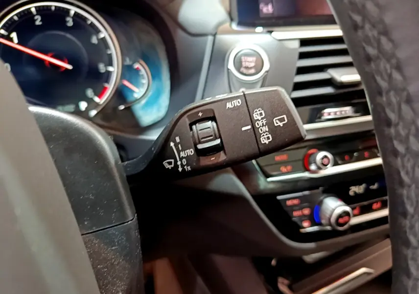 Gros plan sur la commande d’essuie-glace à gauche du volant dans l’habitacle noir d’une BMW X3 2019.