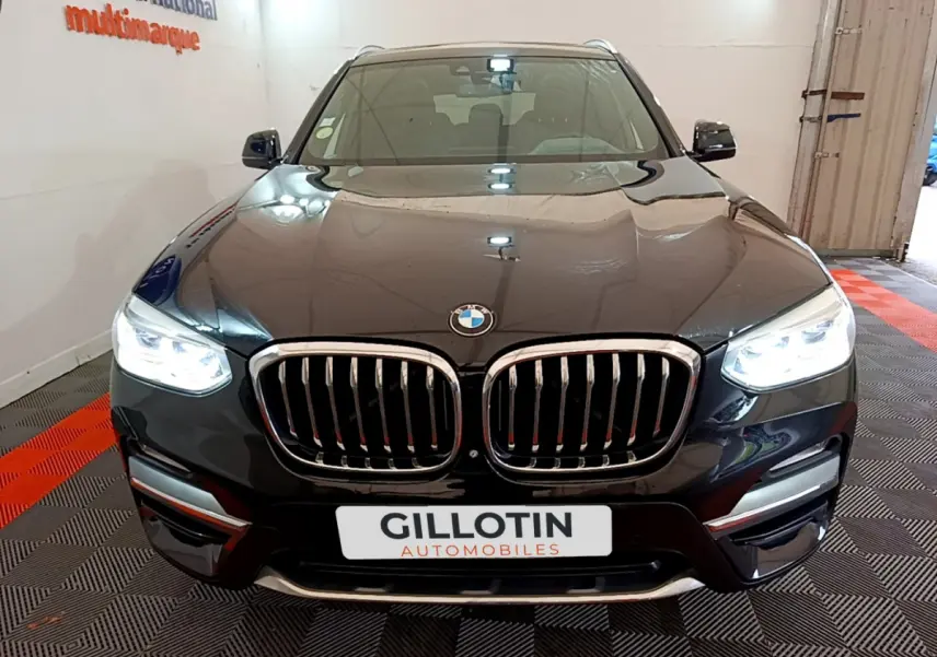 Vue avant d'un BMW X3 noir 2019 avec phares LED allumés et calandre chromée distinctive.