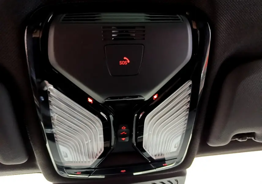 Vue en contre-plongée du plafonnier noir avec bouton SOS rouge allumé dans l’habitacle d’un BMW X3 noir.