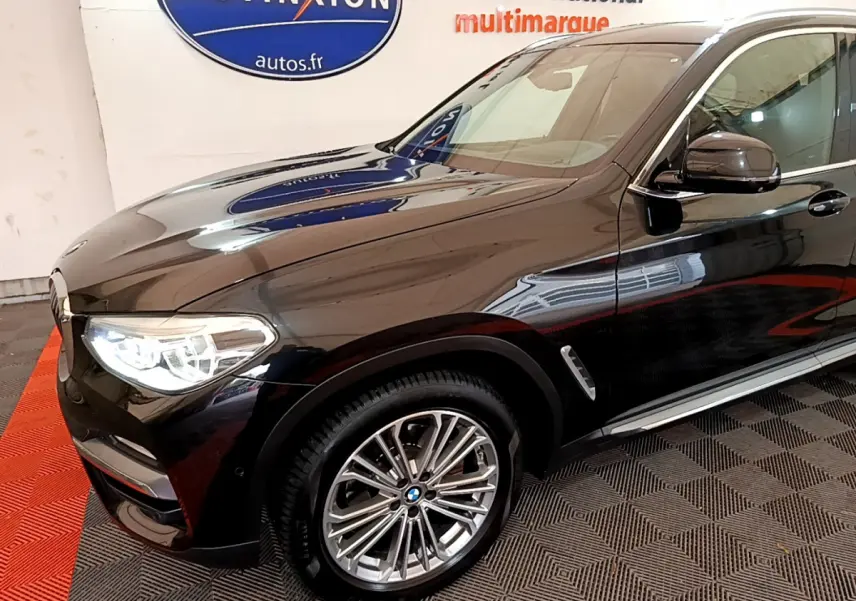 Vue 3/4 avant droit d’un BMW X3 xDrive20d noir brillant, avec jantes alliage et phares LED allumés.