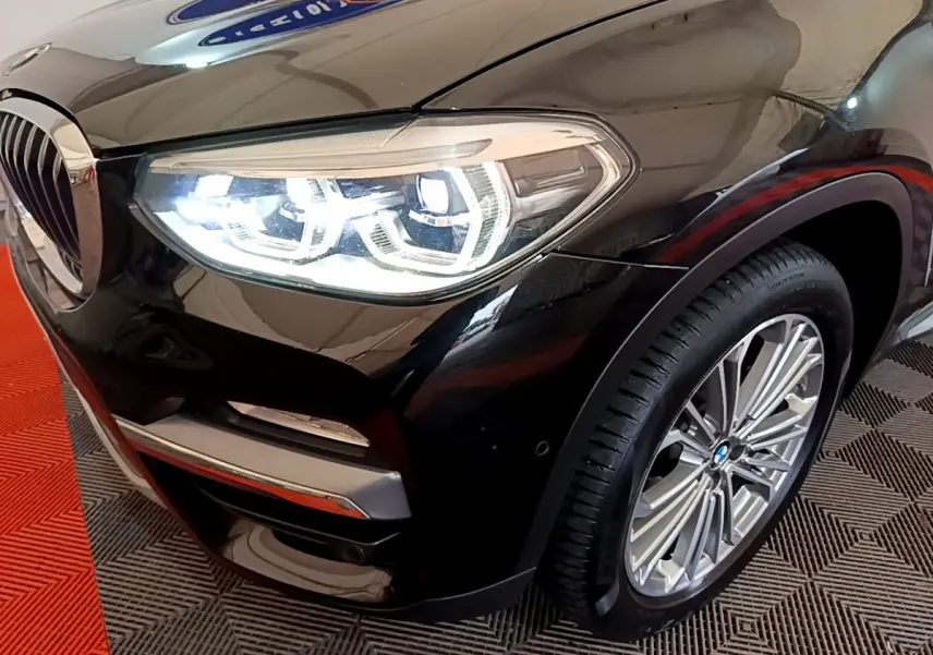 Gros plan sur l’avant droit noir brillant d’un BMW X3 2019 avec phare LED allumé et jante alliage visible.