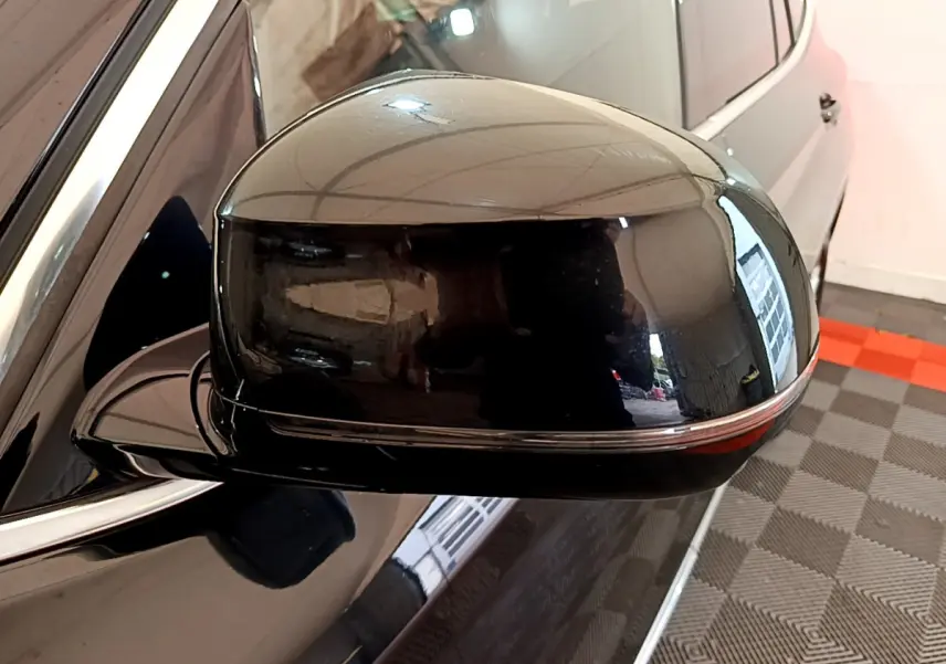 Gros plan sur le rétroviseur côté gauche noir brillant d’un BMW X3 xDrive20d 2019, reflet de l’environnement intérieur visible.