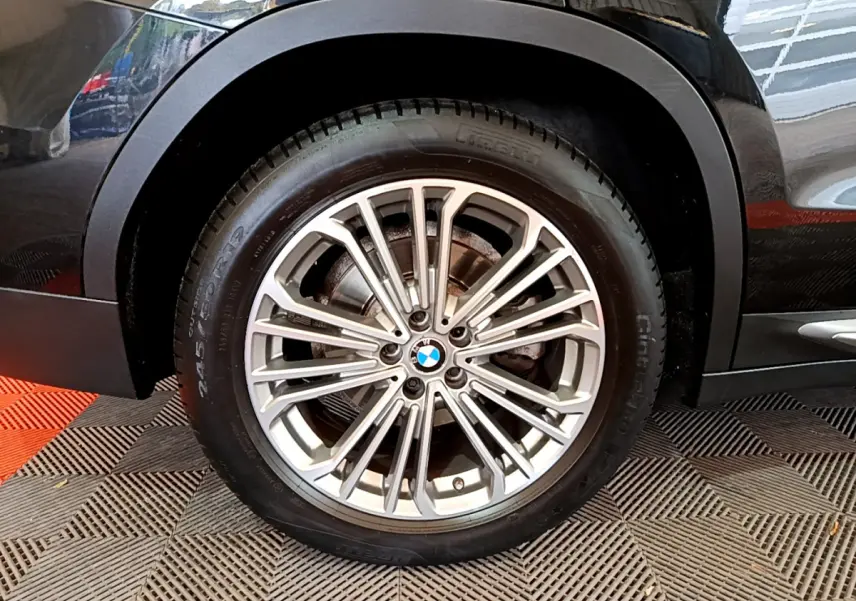 Gros plan sur la roue arrière droite d’un BMW X3 noir, mettant en valeur la jante alliage multi-branches et le logo BMW central.