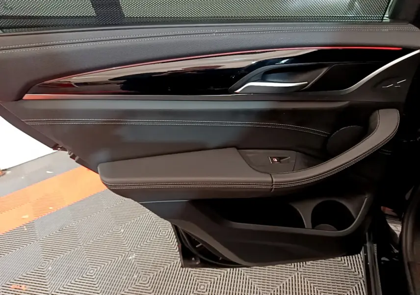 Gros plan sur la porte intérieure côté droit noire du BMW X3 xDrive20d 2019 avec surpiqûres blanches et insert laqué.