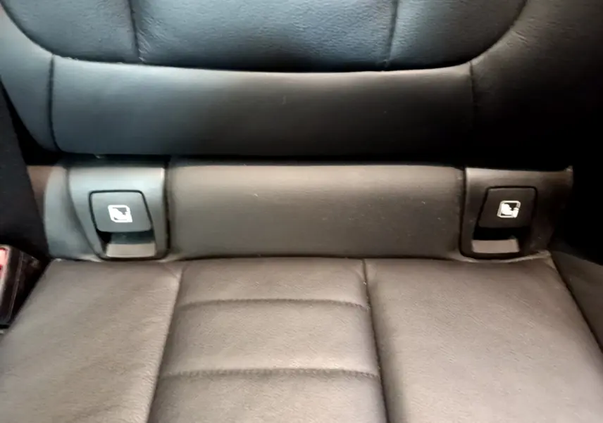 Gros plan sur la banquette arrière noire du BMW X3 avec boutons de rabattement des sièges intégrés.