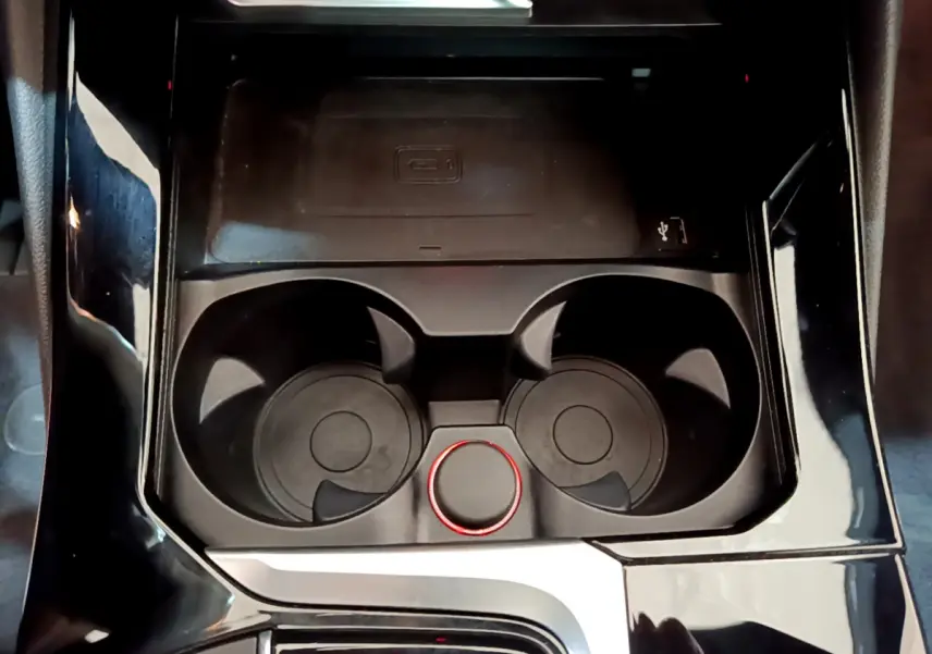 Gros plan sur la console centrale noire de la BMW X3 2019, avec porte-gobelets et molette de contrôle rouge.
