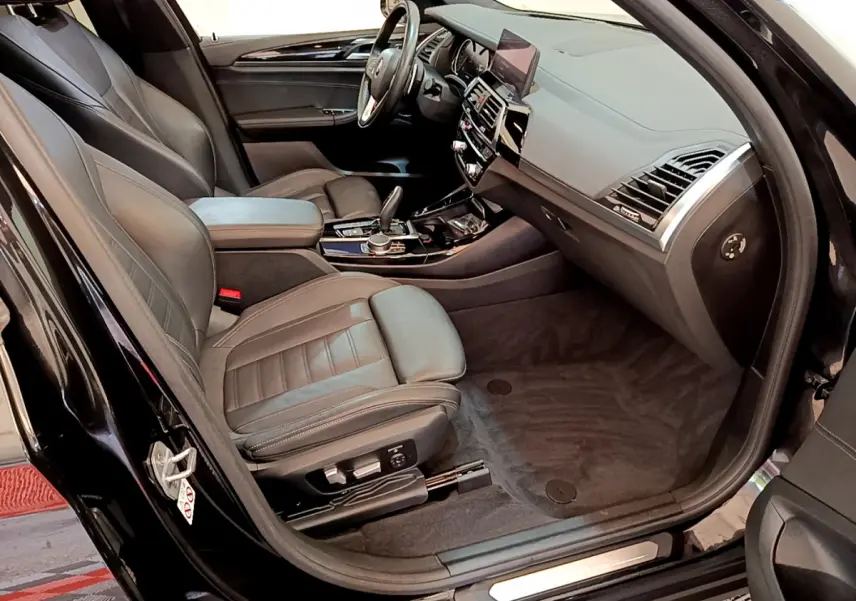 Vue intérieure côté conducteur du BMW X3 noir 2019, mettant en valeur les sièges cuir et le tableau de bord moderne.