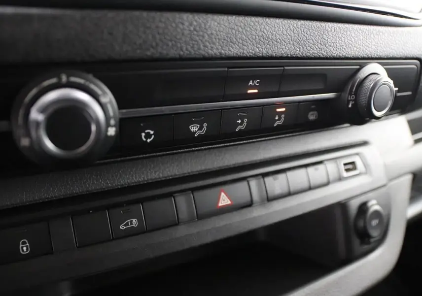 Gros plan sur la console centrale du Citroën Jumpy blanc, montrant les commandes de climatisation et les boutons de sécurité.