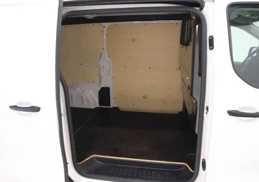 Vue intérieure par la porte latérale ouverte du Citroën Jumpy blanc, montrant l'aménagement bois du fourgon XL.