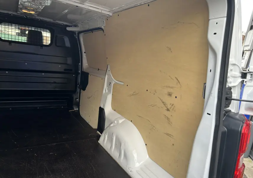 Vue intérieure côté droit du fourgon blanc Citroën Jumpy XL 2019, montrant la cloison bois et le plancher noir.
